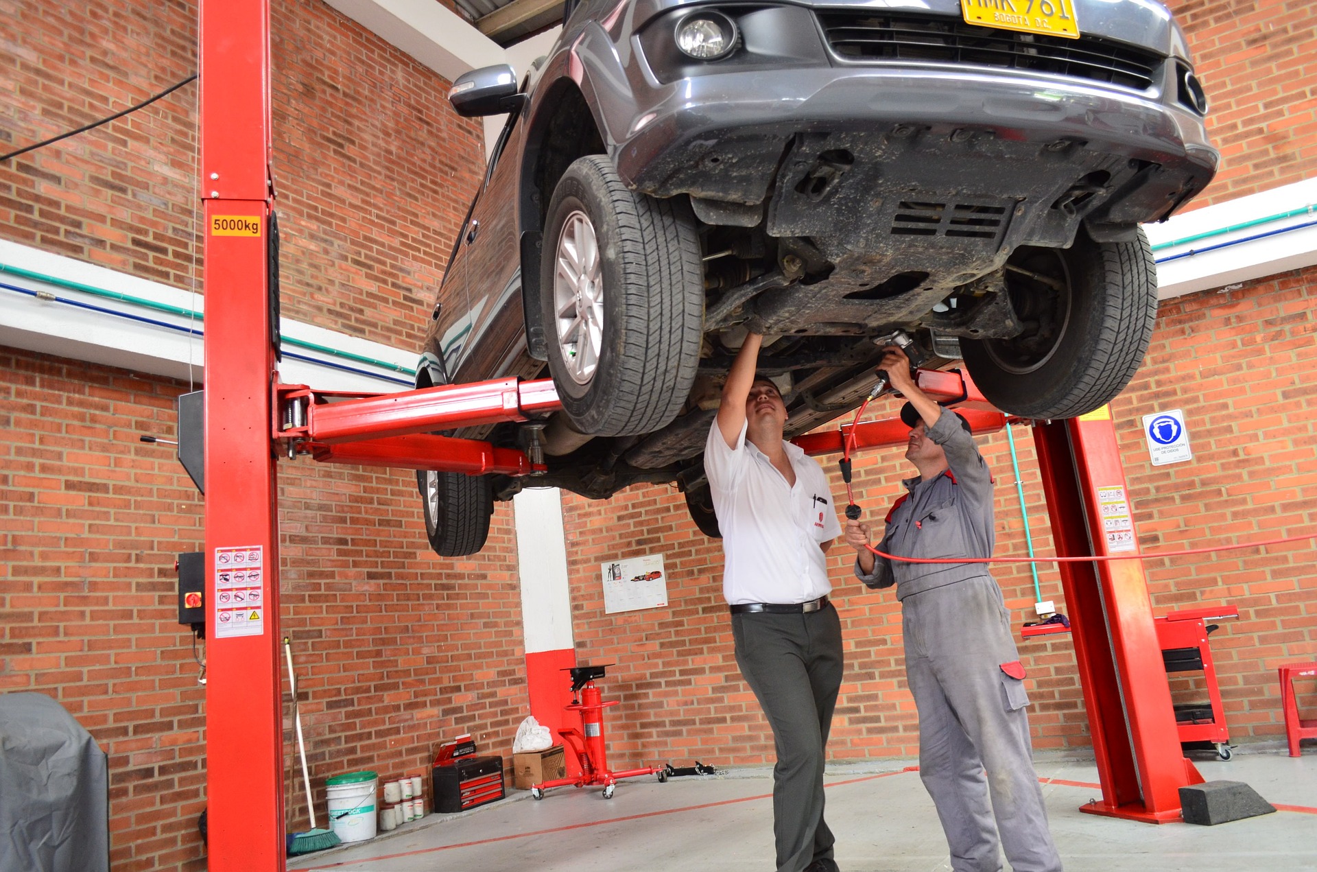 mechanics working on a car that is on a lift
